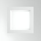 The Radiara-2 Square LED Recessed Downlight 120mm - 15W, 3000K, White is illuminated in a modern, light-colored room. Its minimalist square design with a white frame emits a soft glow from the LED bulb. With an IP65 rating, it ensures both durability and elegance for any stylish space.