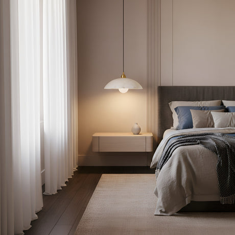 A modern, minimal bedroom with a neatly made bed, neutral bedding, a floating nightstand with a small vase, the Faylen 1 Light Bowl Alabaster Single Pendant Light in soft white & brushed brass, white curtains, and gentle natural light.