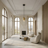 A modern, minimalist living room with large arched windows, cream walls, a marble fireplace, two rounded beige armchairs, a marble coffee table, the Slice Glass Pendant Light - Gold overhead, and city rooftops visible outside.