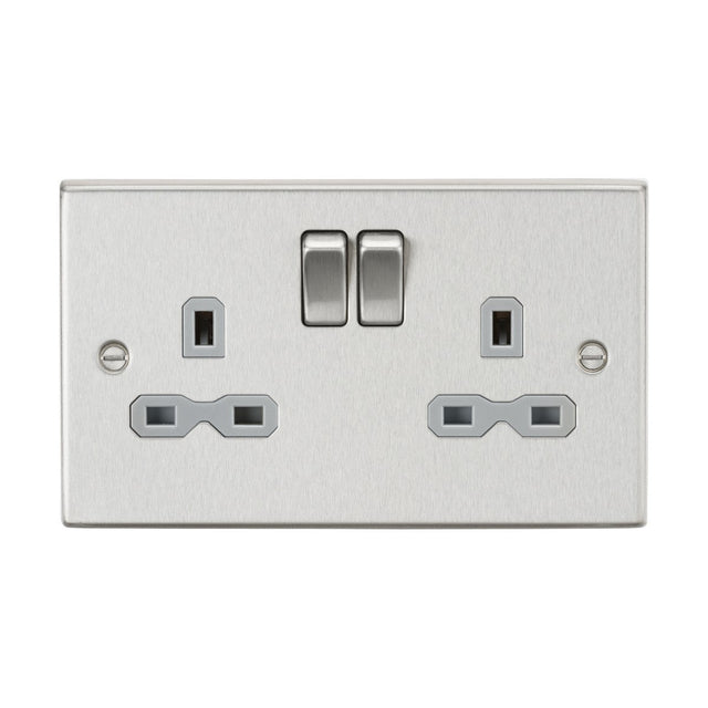 The 13A 2 Gang DP Switched Socket with Twin Earths, featuring a brushed chrome finish and grey insert, showcases a modern square-edge design with two switches above the three-pin sockets. This stylish and contemporary switched socket brings an elegant touch to any environment.