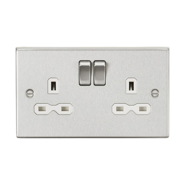 The 13A 2 Gang DP Switched Socket with Twin Earths in brushed chrome boasts a sleek rectangular plate with a square edge design. This socket features two switches positioned above the outlets, each having three holes arranged in the standard UK pattern, and incorporates a stylish white insert to enhance modern elegance and functionality.