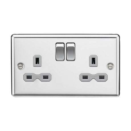 The 13A 2 Gang DP Switched Socket With Twin Earths, featuring a polished chrome finish with a grey insert and rounded edges, adds a decorative touch to any room.