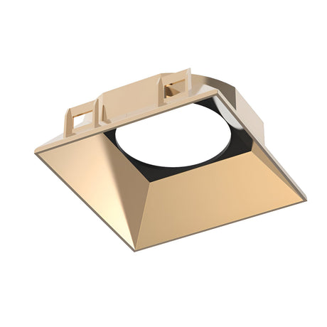 The Glistenis Reflector Square Frame 89mm in gold features an angled, reflective interior and a circular opening at its center. Its modern, geometric design makes it ideal for contemporary lighting installations.