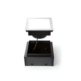 The Zephyra LED Square Recessed Ground Light - 21W, 3000K, Silver is displayed against a white background, highlighting its silver design with a transparent cover. Slightly elevated to show the attached cable, this outdoor lighting solution boasts an IP67 rating for superior durability and weather resistance.