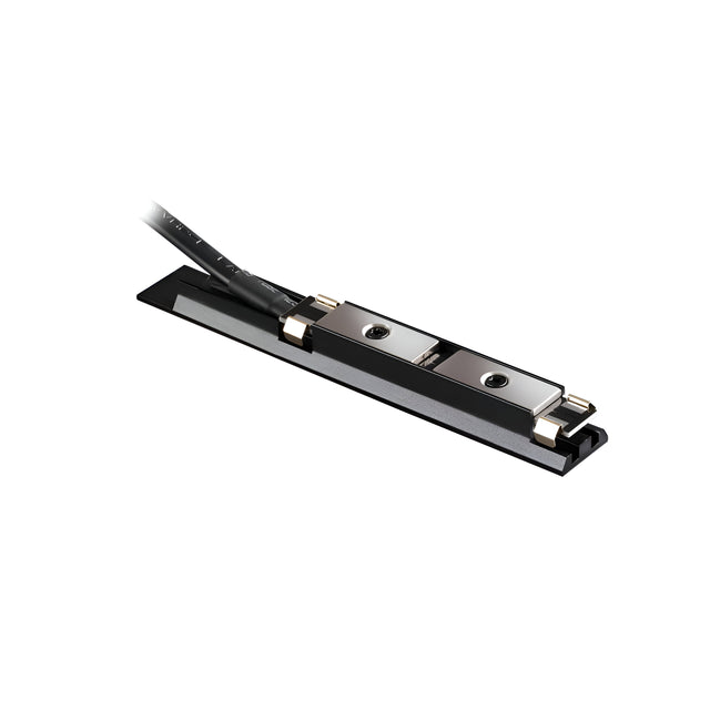 Close-up of the Viora Magnetic Track Lighting Power Input Connector in black, showcasing its sleek, rectangular design with a cable attached, highlighting the metal components on a flat base. The cable emerges from one end, indicating electronic connectivity and customizable cable length for precise installations.