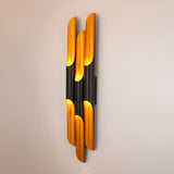 The Stealth 6 Light Wall Light in brass and black features vertically arranged cylinders that emit warm yellow light, casting a soft glow on any wall—an elegant addition to architectural wall lighting design.