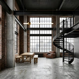 Spacious industrial loft with grid windows, exposed brick walls, concrete floors, a wooden dining table with benches, a leather armchair, and the Sottile LED Horizontal Suspension Light in gold accenting the black spiral staircase to the upper level.