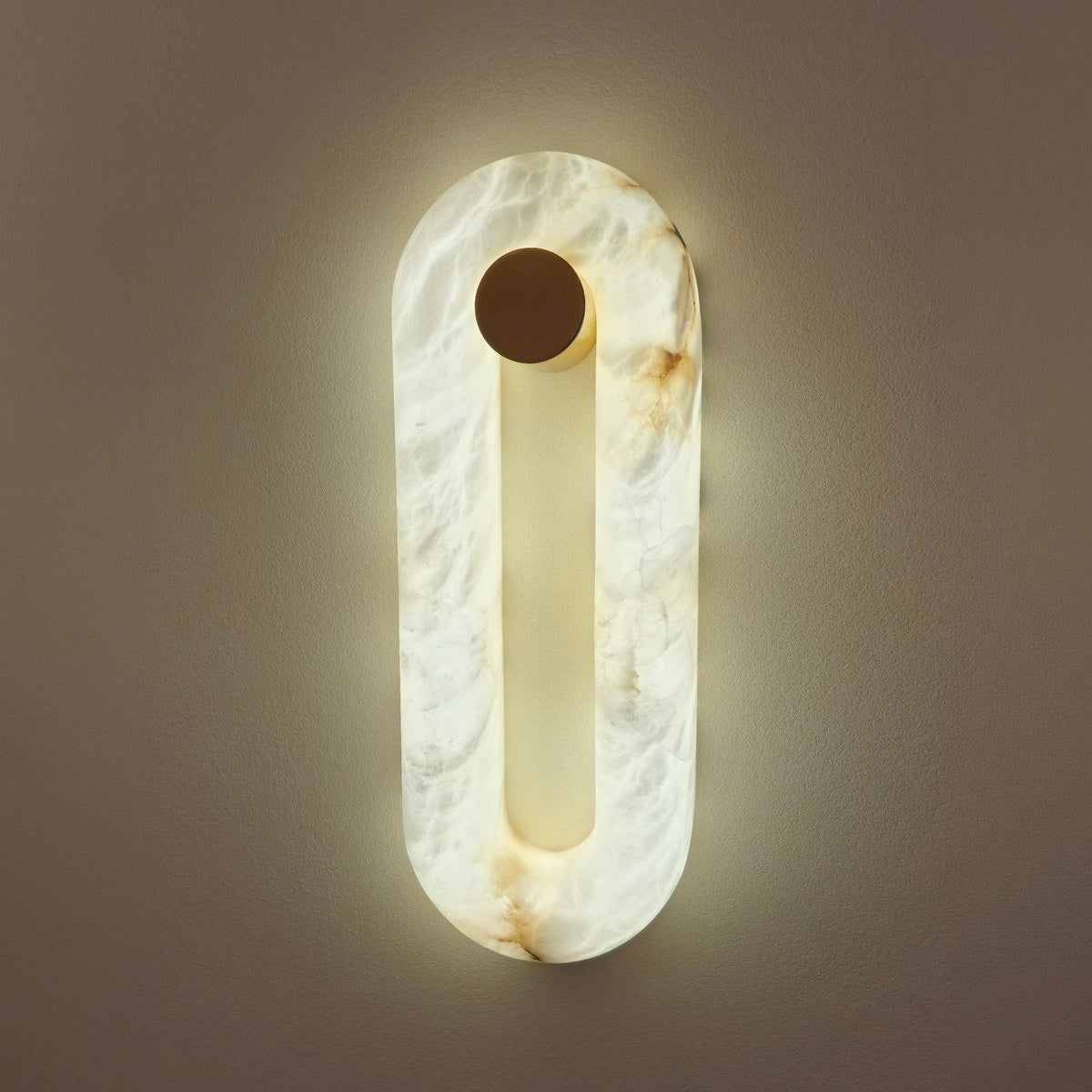 Serava LED Small Alabaster Wall Light in soft white, an oval ring wall light with matt black cylindrical fixing, glowing warm-white against a neutral wall.