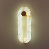 Serava LED Small Alabaster Wall Light in soft white, an oval ring wall light with matt black cylindrical fixing, glowing warm-white against a neutral wall.