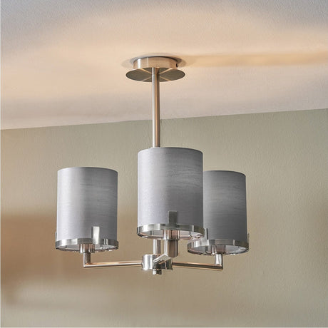 Midland 3-arm pendant light in brushed nickel with three cylindrical grey fabric shades, shown suspended from a ceiling rose in a room with pale walls.