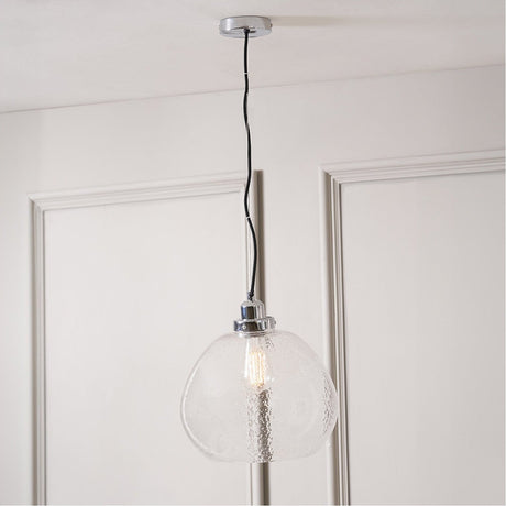 Beja Organic Shape Clear Bubble Glass Pendant Light, 30cm, with chrome fitting and exposed bulb, hanging from a black cord against a panelled white door.