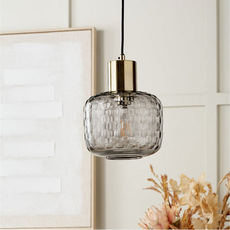 Camille Smoke Grey Circle Design Handcut Glass Pendant Light, 20cm, with a textured woven-pattern glass shade and brass fitting, shown hanging in a neutral living room setting.