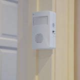 AVSL Mercury motion sensing visitor chime in white ABS housing with PIR sensor, speaker grille and on/off switch, wall-mounted beside a cream door frame.