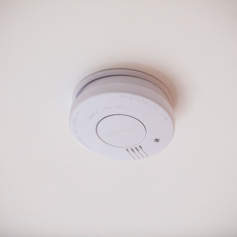 AVSL Mercury photoelectric smoke detector in white, ceiling-mounted with central test/hush button, red LED indicator and side alarm vents.