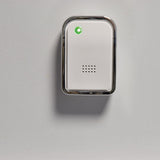 AVSL Mercury wireless door chime receiver wall-mounted on a light background, white casing with chrome trim, speaker grille and illuminated green LED indicator.