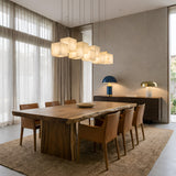 Niori Elmyra 8 Light Linear Alabaster Pendant in soft white, staggered cube shades suspended above a live-edge wood dining table with tan leather chairs.