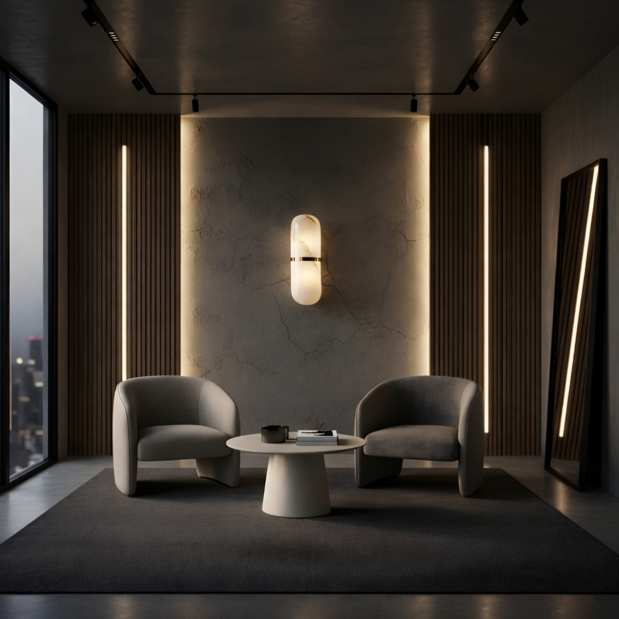 A modern lounge with two armchairs, a round coffee table, and a wall adorned with Ciel LED Cylinder Alabaster Wall Lights in Soft White & Brass. Large windows reveal a city view, and a tall mirror leans stylishly against the wall.