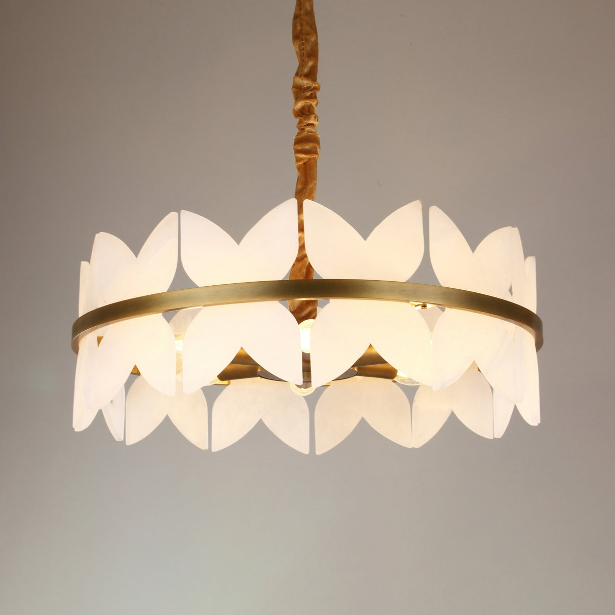 Niori Petraia 6 light chandelier with white alabaster petal panels in two staggered rings around a brushed brass band, hung from a gold fabric cable.