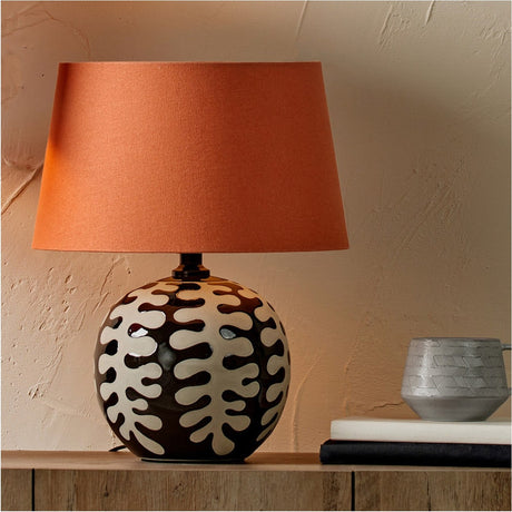 Winston Tobacco Handloom Tapered Lampshade, 45cm, in burnt orange fabric on a patterned ceramic table lamp base, shown in a room setting.