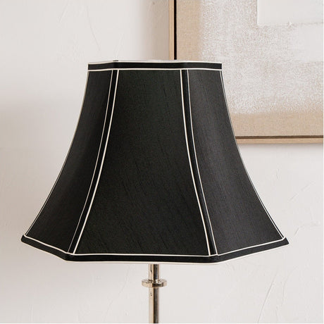 Lyla Black Silk Mix Bowed Lampshade, 40cm, on a lamp base against a plain white wall, with white piped trim along the panel seams and top and bottom edges.