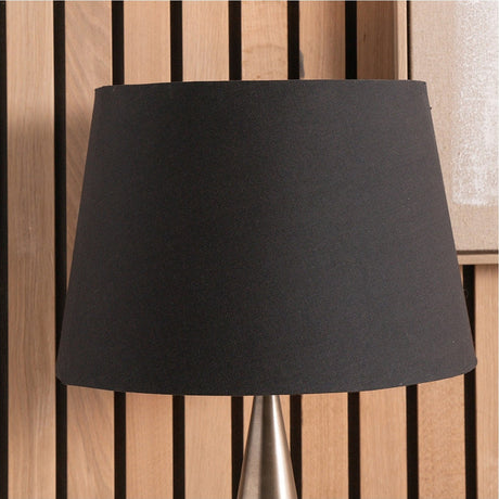 Adelaide Black Tapered Cotton Mix Lampshade, 35cm wide, shown on a table lamp with brushed metal base against a wood slat background.