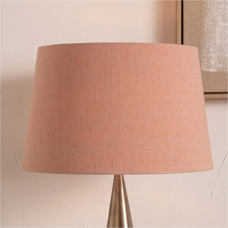 Milos Apricot Linen Tapered Lampshade, 40cm, shown fitted to a tapered brushed metal lamp base against a neutral wall with a framed picture.