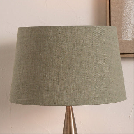 Milos Pistachio Green Linen Tapered Lampshade, 50cm, shown fitted on a brushed metal table lamp base against a plain wall.