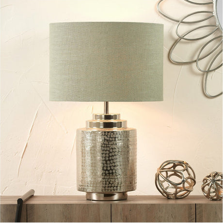 Edward Pistachio Green Linen Cylinder Lampshade, 40cm, shown fitted on a hammered silver-tone table lamp base in a home setting.