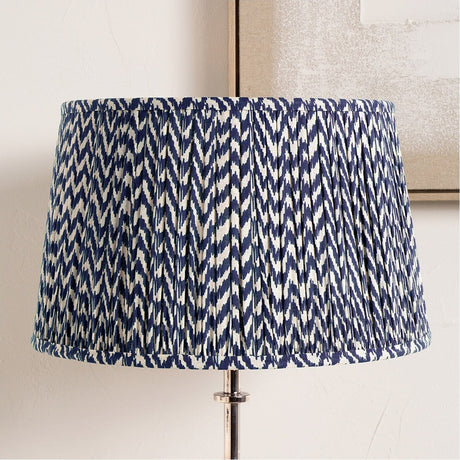 Vienna Blue Chevron Pleated Lampshade, 50cm, in a drum shape with pleated blue and white zigzag fabric, fitted on a chrome table lamp base.