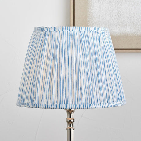 Thiago Ocean Blue Stripe Pleated Tapered Lampshade, 30cm, fitted on a chrome table lamp base, shown against a plain white wall.