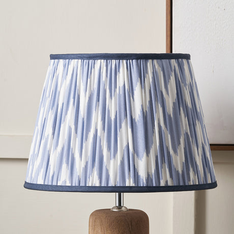 Kamilah Blue Chevron Pleated Tapered Lampshade, 45cm, in blue and white chevron fabric with navy trim, shown fitted on a wooden lamp base against a light background.