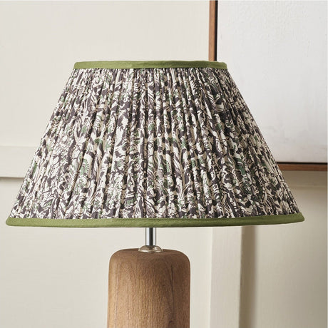 Ornella pleated empire lamp shade, 35cm, with green floral fabric pattern and green trim, shown on a wooden lamp base against a light wall.
