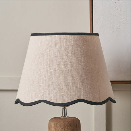 Tabitha Cream Jute Scalloped Edge Tapered Lamp Shade, 30cm, with black trim, shown on a wooden lamp base against a neutral wall.