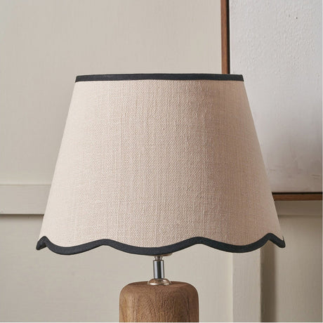 Tabitha Cream Jute Scalloped Edge Tapered Lamp Shade, 35cm, with black trim, shown on a wooden lamp base against a light neutral wall.