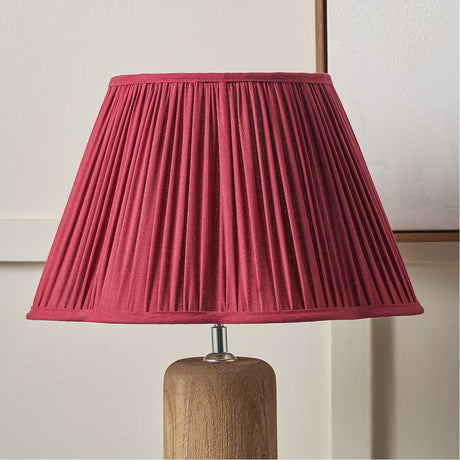 Malia Mulberry Red Pleated Scalloped Tapered Lamp Shade, 30cm, fitted on a wooden table lamp base against a light neutral wall.