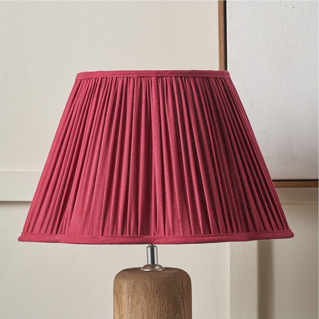Malia Mulberry Red Pleated Scalloped Tapered Lamp Shade, 40cm, in fabric on a wooden lamp base, set against a light neutral wall.