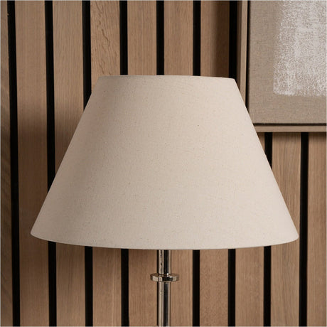 Seychelles Cream Slubby Cotton Empire Lampshade, 50cm, in cream fabric with a tapered shape, shown fitted on a chrome table lamp base against a wood-slat wall.