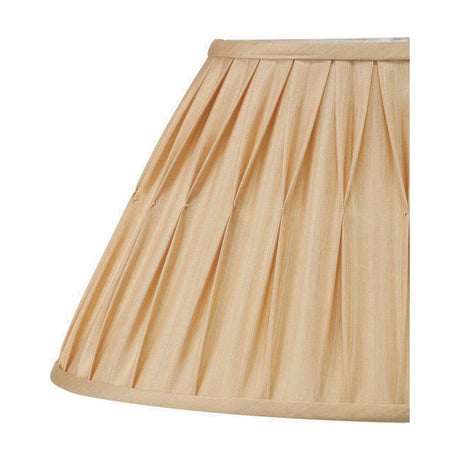 Close-up of the Garbo Gold Silk Mix Pinch Pleated Tapered Lampshade, 25cm, showing gathered pleats and trim edging in a warm gold fabric against a plain white background.