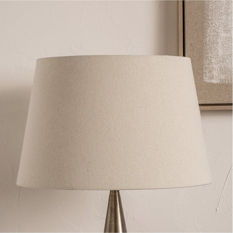 Coast Cream Calico Tapered Lampshade - 55cm in fabric on a lamp base, shown against a light wall with a framed picture nearby.
