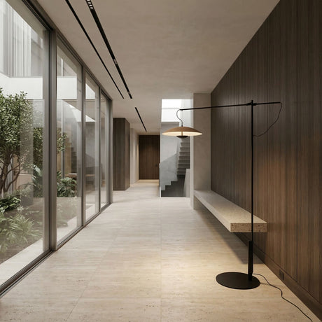 Minimalist hallway with large glass windows to a garden, wood-paneled walls, a floating stone bench, tile floors, and stairs. The space is softly lit by sleek modern fixtures and the Ginger LED Large Floor Lamp in Black & Oak.
