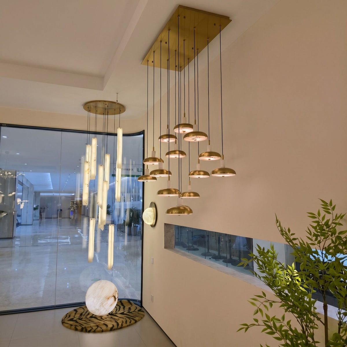 Aurevia 14-Light LED Linear Alabaster Chandelier with brushed brass canopy and staggered domed drops, shown in a hallway ceiling installation.