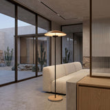 A modern living room with a white textured sofa, large glass windows overlooking a minimalist desert garden with cacti, and neutral tones. The space features minimalist decor and a sleek Ginger LED Floor Lamp - Black & Brown.