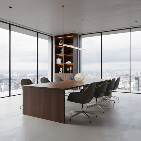 A modern conference room with a long wooden table, eight gray wheeled chairs, floor-to-ceiling windows with city views, built-in shelves, minimalist decor, and an Illuma Small Pebble Alabaster Table Lamp – Soft White.