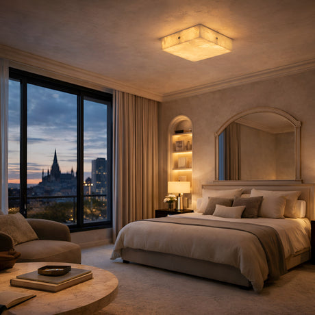 A cozy, elegant bedroom features a large bed, plush bedding, and ambient lighting from the Cadris LED Small Square Alabaster Flush Ceiling Light—Soft White & Brushed Brass—above built-in shelves and a bedside table with a brushed brass lamp and mirror.