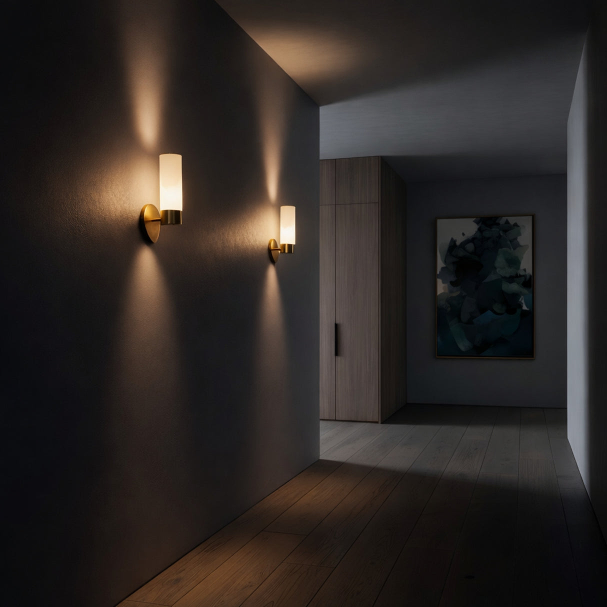 A dimly lit hallway with two Solique 1 Light Double Cylinder Alabaster Wall Lights in Soft White & Brass casting warm light on dark walls, wooden flooring, and a large abstract painting near light wooden cabinets.