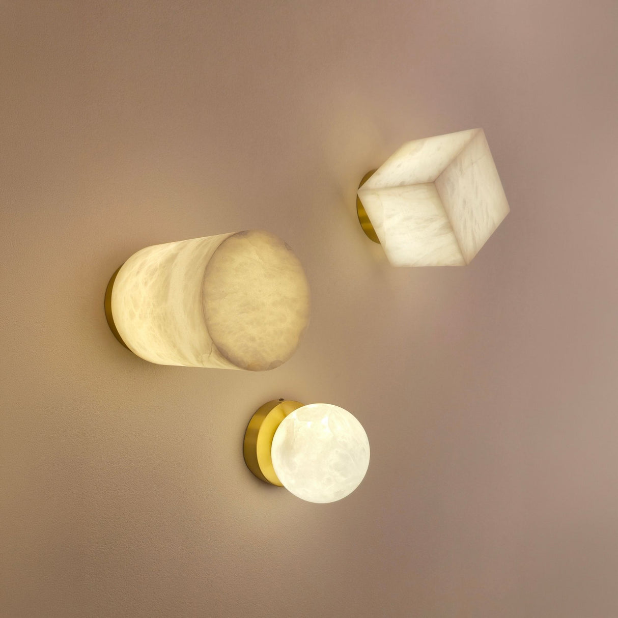 Bravora 1-Light Alabaster Globe Semi-Flush Ceiling Light with brushed brass canopy, shown lit alongside alabaster wall lights on a neutral wall.