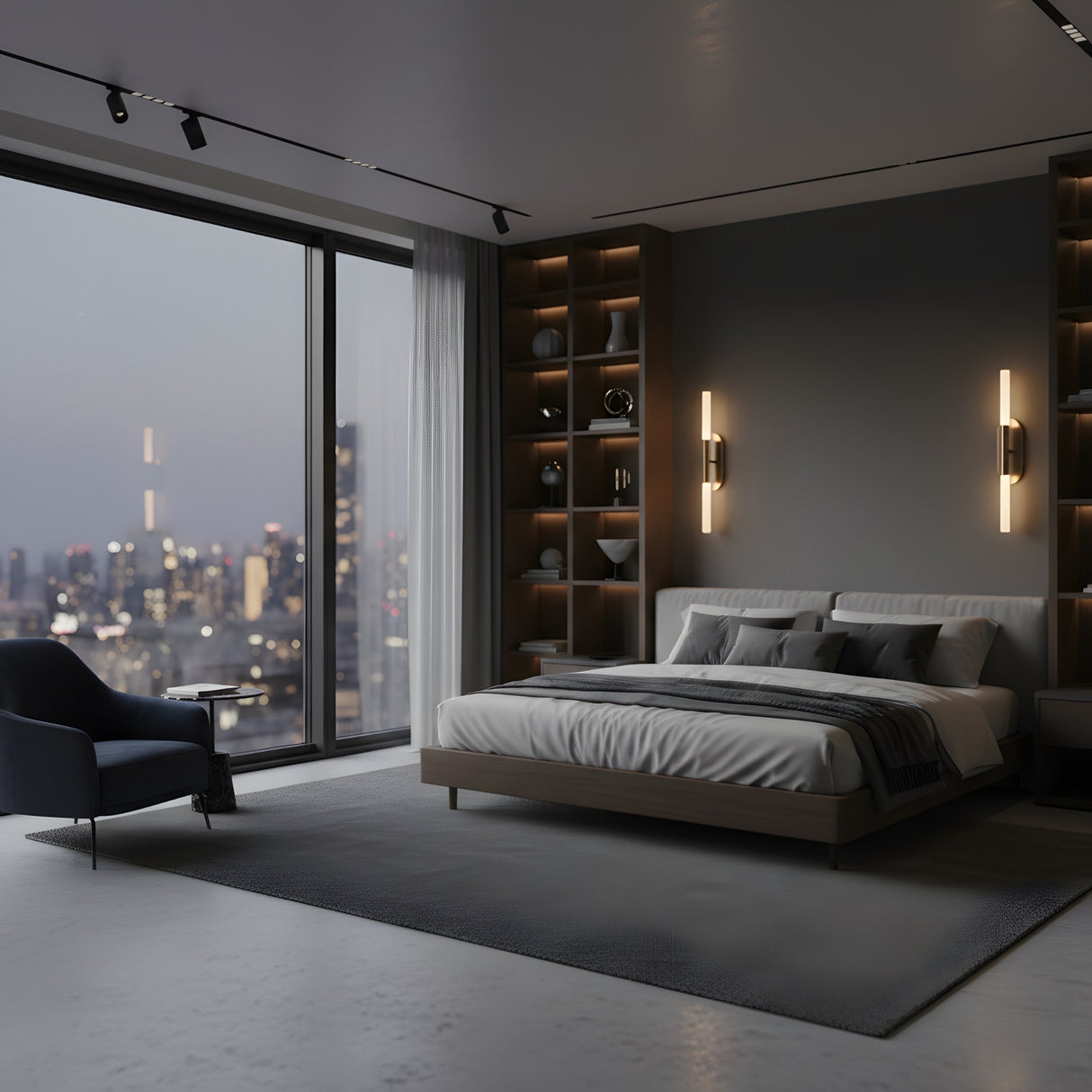 A modern bedroom with a large bed, built-in shelves, an Aurelian LED Double Column Alabaster Wall Light in brushed brass & soft white, a dark armchair, and floor-to-ceiling windows overlooking the city skyline at dusk.