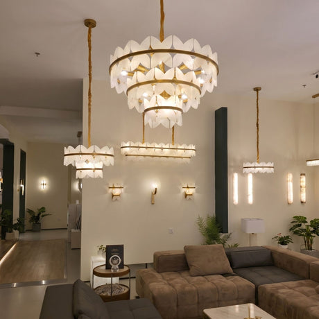 Petraia 2-tier floral alabaster chandelier with brushed brass frame, illuminated in a living room above a sofa and side lighting.