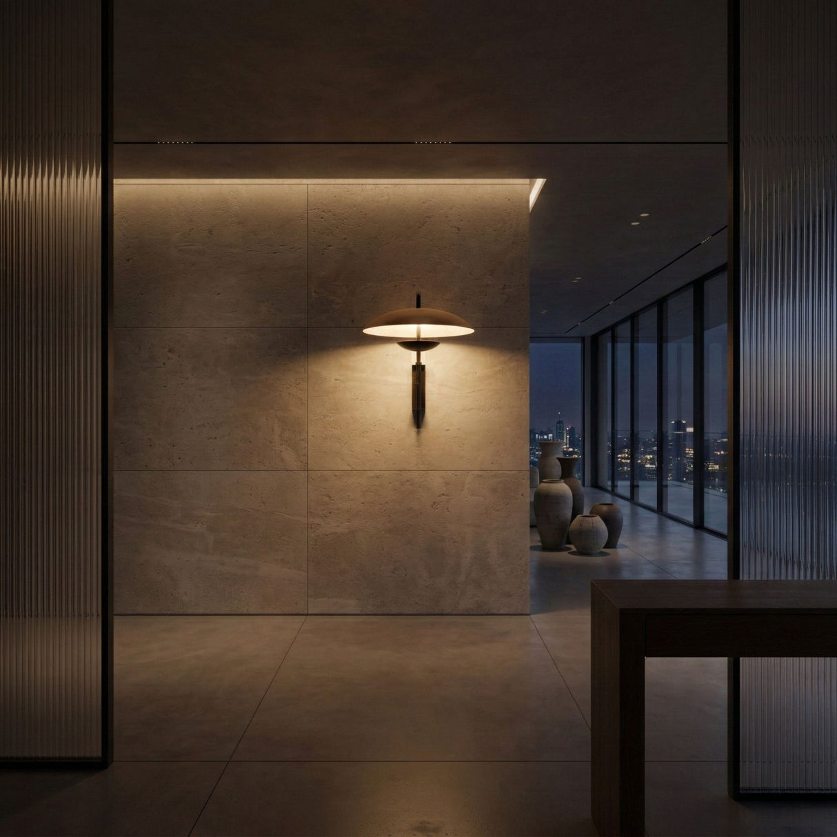 Niori Ginger LED Wall Light in black and brown mounted on a stone wall in a dim modern interior with floor-to-ceiling windows and a city night view.