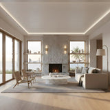 A modern, minimalist living room with a stone fireplace, light wood floor, beige sofa, round marble coffee table, large windows with a coastal view, and Aurelian LED Double Column Alabaster Wall Lights in Brushed Brass & Soft White.
